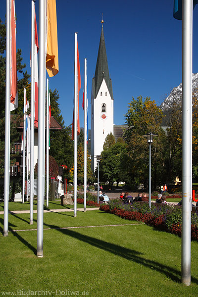 Oberstdorf Kurpark Fahnen Maste Kirchturm Hochformat Urlauber Parkidylle in Bild