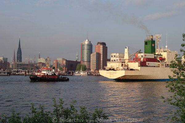 Schlepper eskortiert Containerschiff auf Elbe vor Hamburg-Skyline