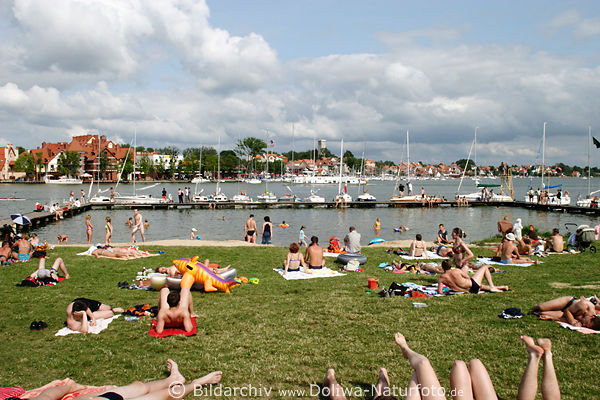 Badestrand Nikolaiken Menschen am See in Masuren Urlaub am Wasser mit Stadtpanorama