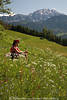 1202182_Mdchen auf Blumenwiese Berghang Grngras gelbwei Blten Naturfotoportrt in Sonne vor Gipfelfelsen sitzen