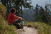 Frau am Bergwaldpfad Naturportrt in Rotkleidung sitzen in Sonnenschein