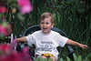 3745_ Kleiner Bub im Garten, Junge lachend auf Stuhl zwischen Blumen, Kind männlich in Natur