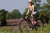 Mädchen lächeln Radfahren unter Sonnenhut blühende Heidelandschaf