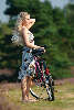 Blondes Fräulein im Kleid stehen mit Sonnenhut Foto hübsches Mädchen am Fahrrad Porträt auf Wanderweg