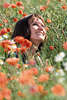 Frau im Klatschmohn fröhlich sonnen, Hoffnung Freude in Rotblumen lächeln in Blumenfeld sitzen