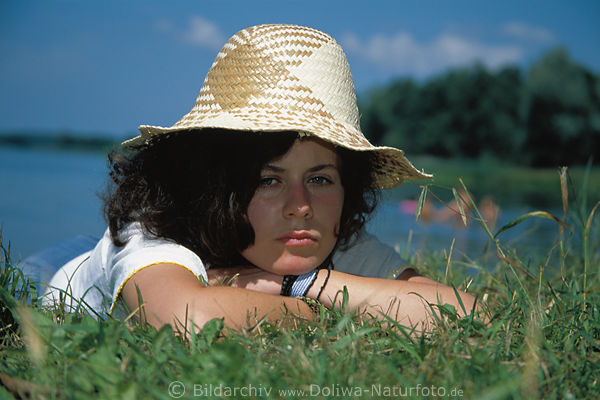 Sonnenhut-Frau am Seeufer Wasserblick in Gras liegend Fotoportrt