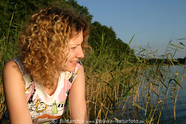 Blondine in Schilf See Portrait Mdchen zerzaustes Haar Strhnen in Abendsonne