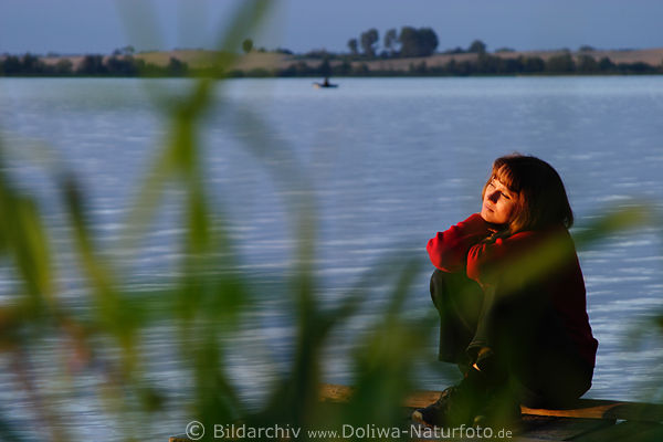 Frau am See Ufer Wassersteg romantische Abendsonne vertrumt hinter Schilf