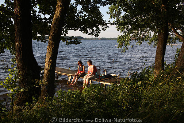Frauen am Seewasser Bcke Steg Girl-Paar unter Bumen sitzen in Naturbild
