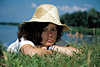 Sonnenhut-Frau am Seeufer Wasserblick in Gras liegend Fotoporträt