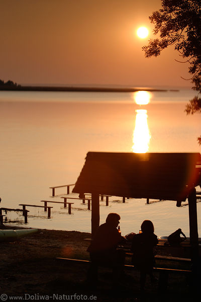 Frauen-Paar am Seeufer vor Sonne ber Wasser strahlend