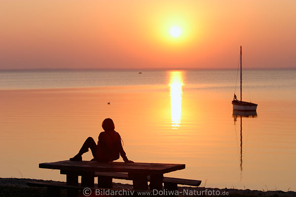 Seeufertisch Frau in roter Sonnenuntergang ber Boot in Wasser