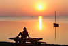 Seeufertisch Frau in roter Sonnenuntergang über Boot in Wasser