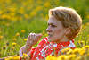 Blondine hübsche Frau im Blütenfeld Foto mit Grashalm im Mund liegen in Blumen