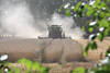 Mahd Staubwolke um Mhdrescher in Foto Getreidefeld maehen Erntearbeit in Gegenlicht durch Grnbltter