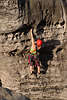 710187_ Frau Alpinistin, Kletterin an Bergwand, Felswand mit Löchern & Spalten mit Haken & Seilen hängen und klettern
