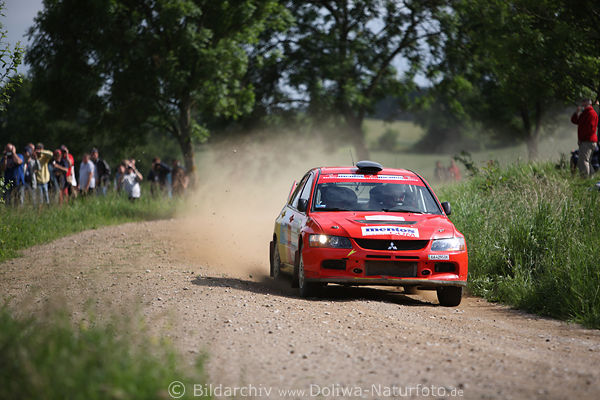 Rally-Polen roter Mitsubishi auf Grnstrecke Sandsteinpiste vor Fans am Wegesrand