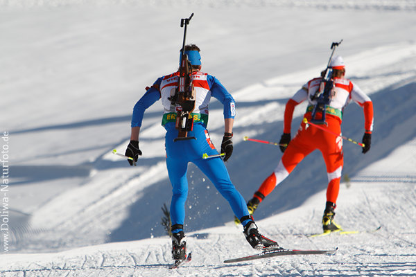 Biathleten Skipaar Skilauf auf schneeweissen Loipe mit Gewehren im Lauf auf Biathlonstrecke