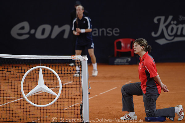 Tennis Ballmdchen kniend am Tennisnetz mit Mercedes-Stern vor Spieler