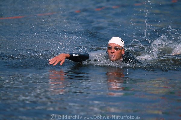Freistil-Schwimmer in Wasserspritzer ausgestreckte Hand frontal Triathlon-Dynamikbild