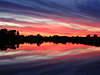 Rotblaue Wolkenstimmung am Himmel über See morgens vor Sonnenaufgang
