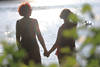 Hand in Hand in Jenseitslicht Sonnenreflexe über Frauenpaar Silhouetten am Wasser Romantikfoto