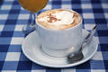 Tasse Cappuccino mit Sahne Foto auf karierter Tischdecke Caf Warmgetrnk