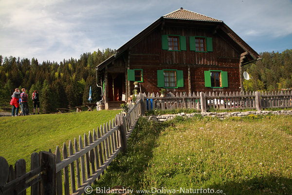 Waisacher Almgasthtte Foto Holzhaus grne Fensterrahmen Wiesenzaun mit Wanderer