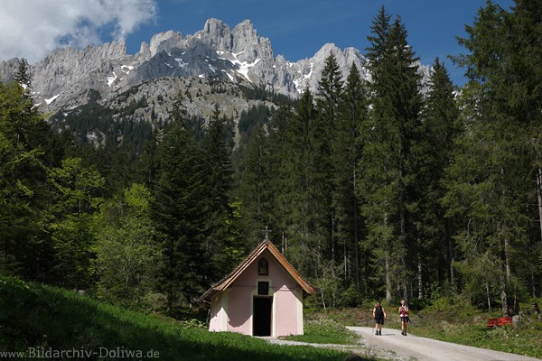 Tannbichlkapelle unter Wilder Kaiser Felsen Bergpanorama Wanderer Paar auf Waldweg