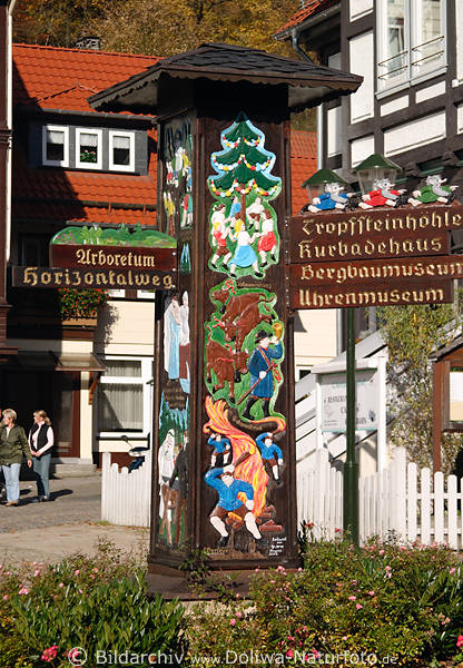 Bunte Schildsule aus Holz mit eingeritzten Darstellungen wie Kuhaustrieb