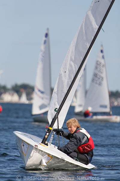 Kieler Woche junger Segler Foto in Segelboot vor Jachten in Ferne