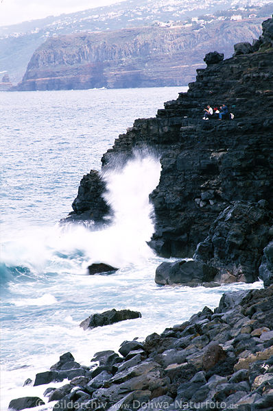 Angler an Felsen vor Meerwellen Wassergischt