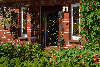 58943_Undeloh 21 Pension Schröder schöne Hausfassade Foto Eingangstür im Garten geschmückt mit Grünpflanzen
