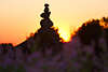 Steinpyramiden Steintroll Silhouette in violett Heideblüten am Horizont glühender Sonne