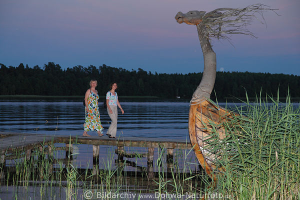 Frauenpaar auf Seesteg zum Galinderboot im Schilf abends in Masuren Beldahnsee