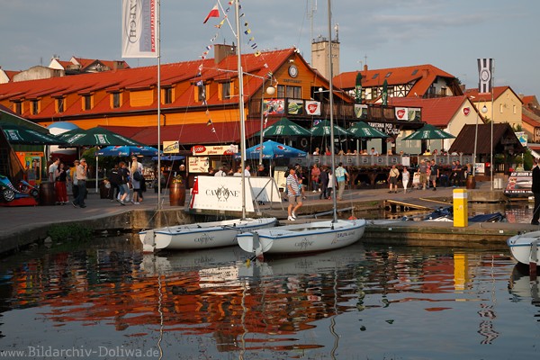 Seglerdorf Nikolaiken Masuren Port Kneipen Besucher am Ufer Mikolajki See Boote in Wasser