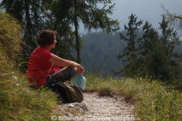 Frau am Bergwaldpfad Naturportrt in Rotkleidung sitzen in Sonnenschein