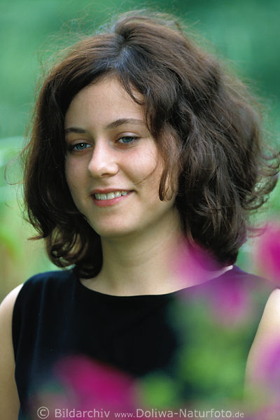 Haarflle Frau in Schwarz Portrait in bunten Blumen