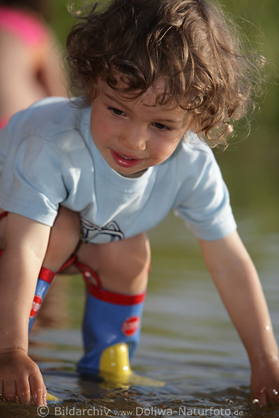 Kind gebckt in Wasser spielen Junge Nachwuchs Sprossling Gesicht