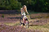 Blondes hbsches Mdel radfahren frhlich in Heideblte mit Fahrrad Foto
