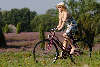 Mädel auf Rad in Heideblüte radeln vor Schafstall blondes Fräulein in Sonnenhut