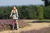 Mädchen mit Fahrrad radeln in Heide Rad-Wanderweg blühende Erika-Landschaft