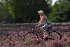 Model mit Sonnenhut Fahrrad fahren in blühender Heide