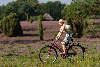 Mädel mit Sonnenhut fahrradfahren vor Schafstall blond Girl Foto in Heidelandschaft