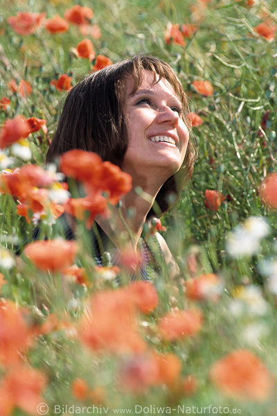 Frau in Klatschmohn fröhlich sonnen in Rotblumen lächeln