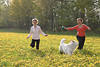 Frauen laufen in Blütenfeld mit Hund durch Gelbblumen