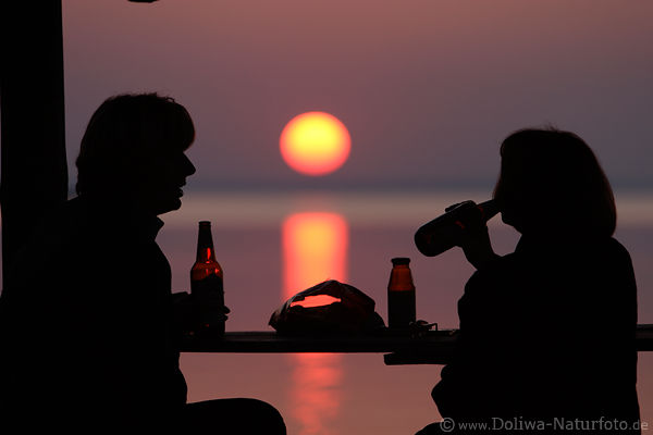 Paar-Silhouetten trinken vor Sonnenkugel ber See lila Naturschauspiel