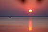 Sonne über Seewasser rosarot Abendfarben mit Fischerboot