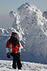 101918_Wintermode: Mädchen dick eingepackt in Winterkleidung Porträt vor weißen Tannenriesen in Schnee & Frost