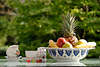 52555_ Obstteller auf Gartentisch mit Kaffeetasse, Obstschüssel mit Ananas, Banane, Apfel, Birne in Bild